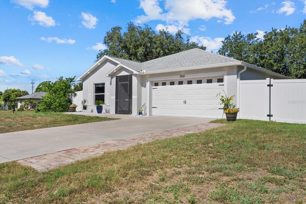 A single-story house with a white garage, gray exterior, and a white vinyl privacy fence — 3561 SHAWN STREET, PORT CHARLOTTE, FL