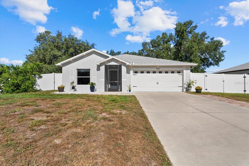 A single-story house with a white garage, gray exterior, and a white vinyl fence — 3561 SHAWN STREET, PORT CHARLOTTE, FL