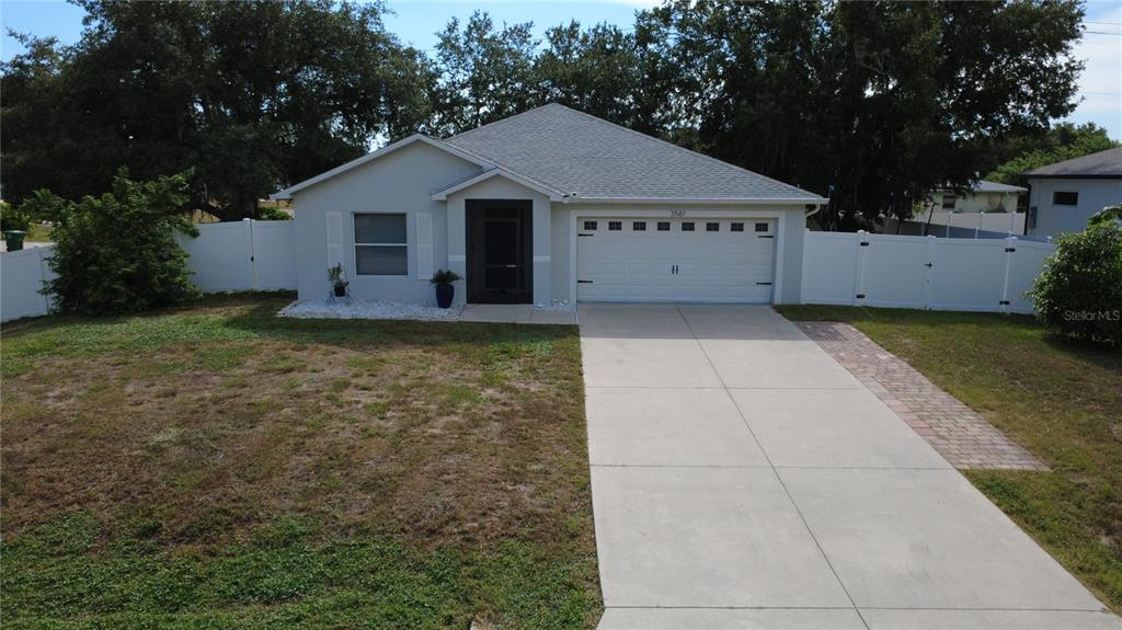 A single-story house with a white garage, concrete driveway, and white vinyl privacy fence — 3561 SHAWN STREET, PORT CHARLOTTE, FL
