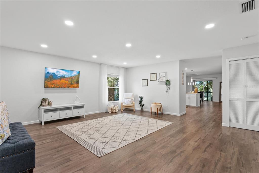 A living room features light gray walls, wood-look flooring, a white media console, and recessed lighting — 3561 SHAWN STREET, PORT CHARLOTTE, FL