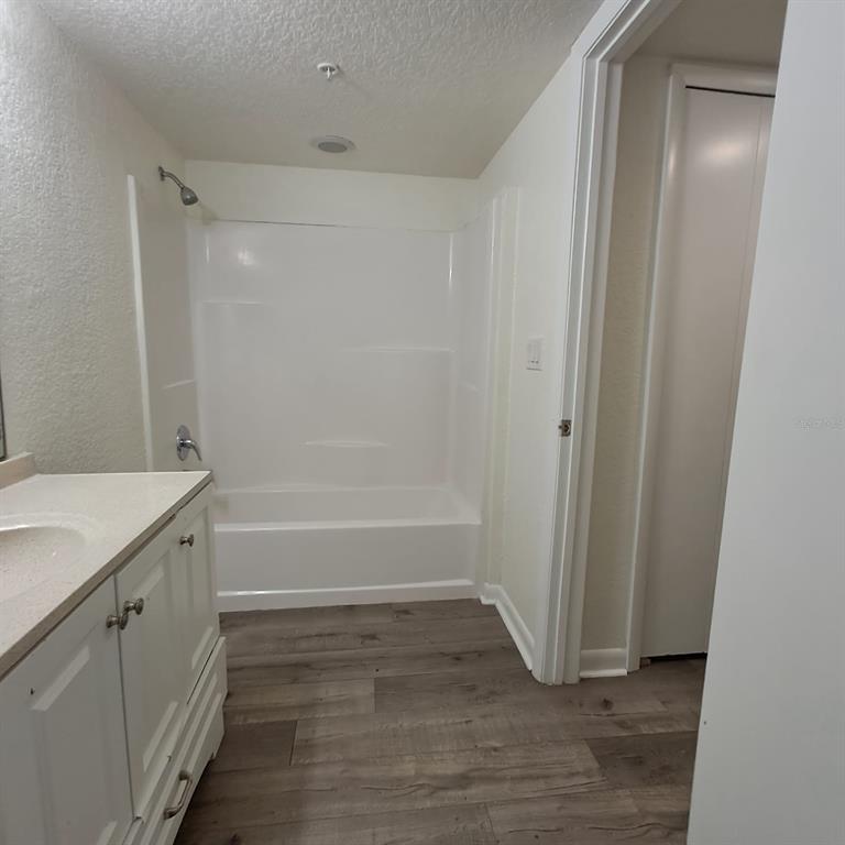 A bathroom features a white vanity, a tub-shower combination, and wood-look flooring — 2323 MCCOY ROAD UNIT 711, ORLANDO, FL