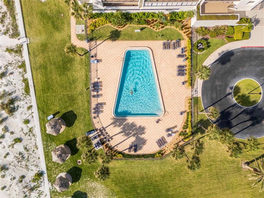 An aerial view shows a trapezoidal swimming pool surrounded by lounge chairs and landscaping — 1460 GULF BOULEVARD UNIT 412, CLEARWATER BEACH, FL