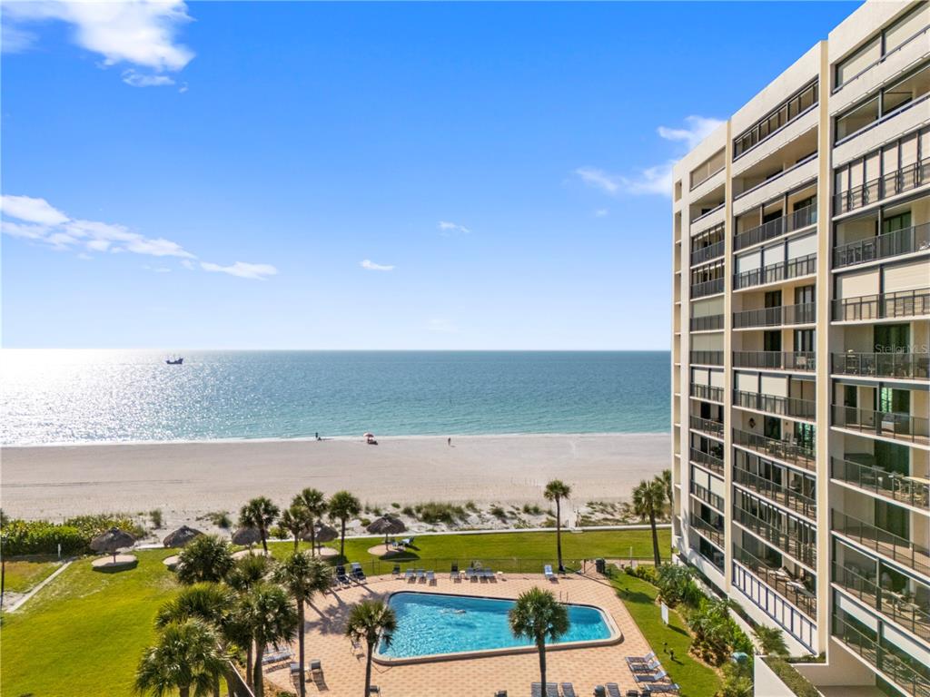 An elevated view of a beach, swimming pool, and a multi-story residential building — 1460 GULF BOULEVARD UNIT 412, CLEARWATER BEACH, FL