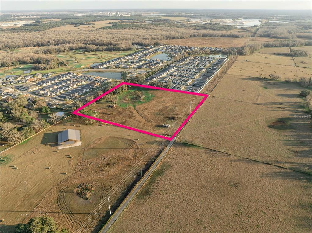 An aerial view shows a vacant, rectangular plot of land outlined in pink near residential neighborhoods — 2619 COUNTY ROAD 523, WILDWOOD, FL