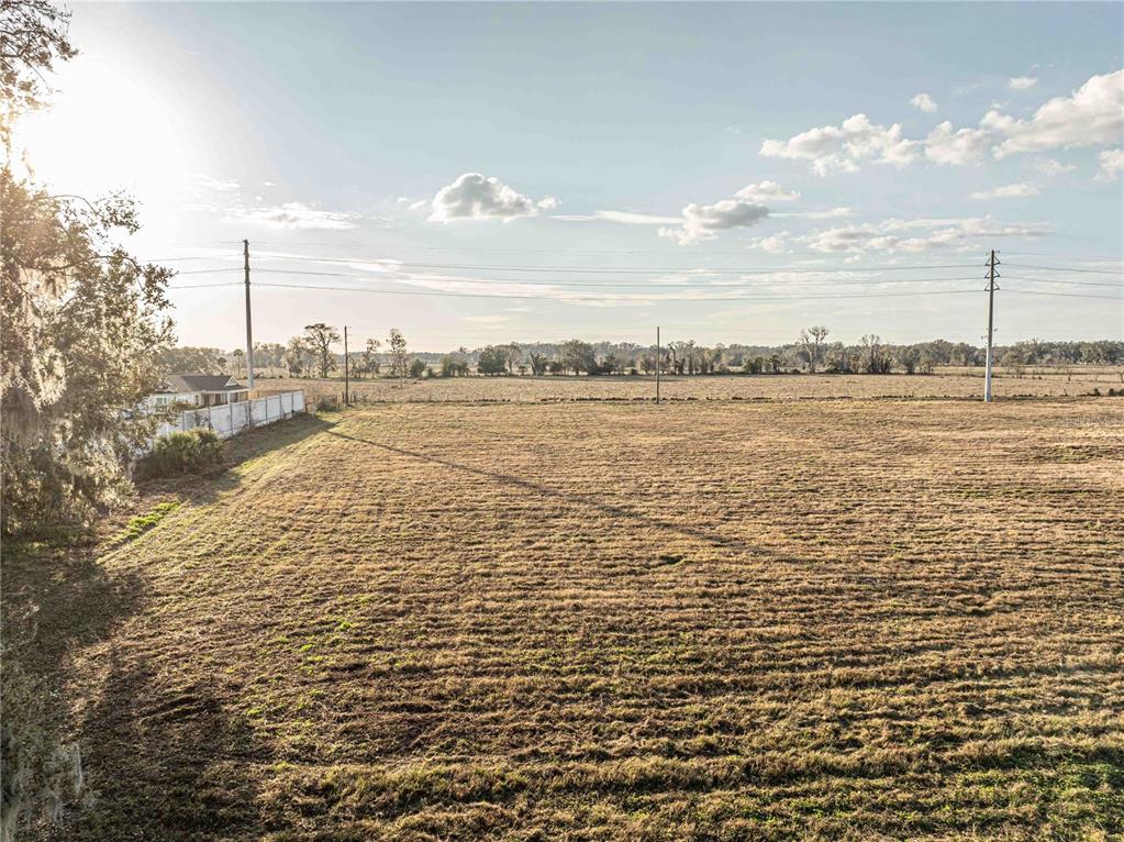 A wide, flat, grassy field under a bright sky with power lines in the distance — 2619 COUNTY ROAD 523, WILDWOOD, FL