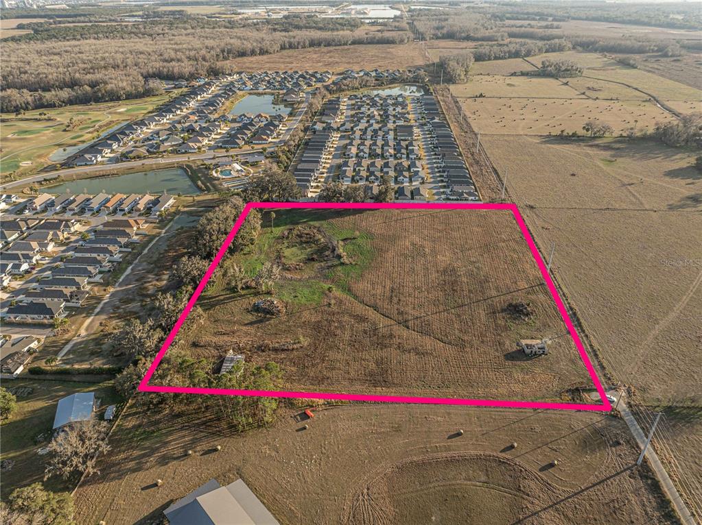 An aerial view shows a large, rectangular vacant lot outlined in pink next to residential neighborhoods — 2619 COUNTY ROAD 523, WILDWOOD, FL