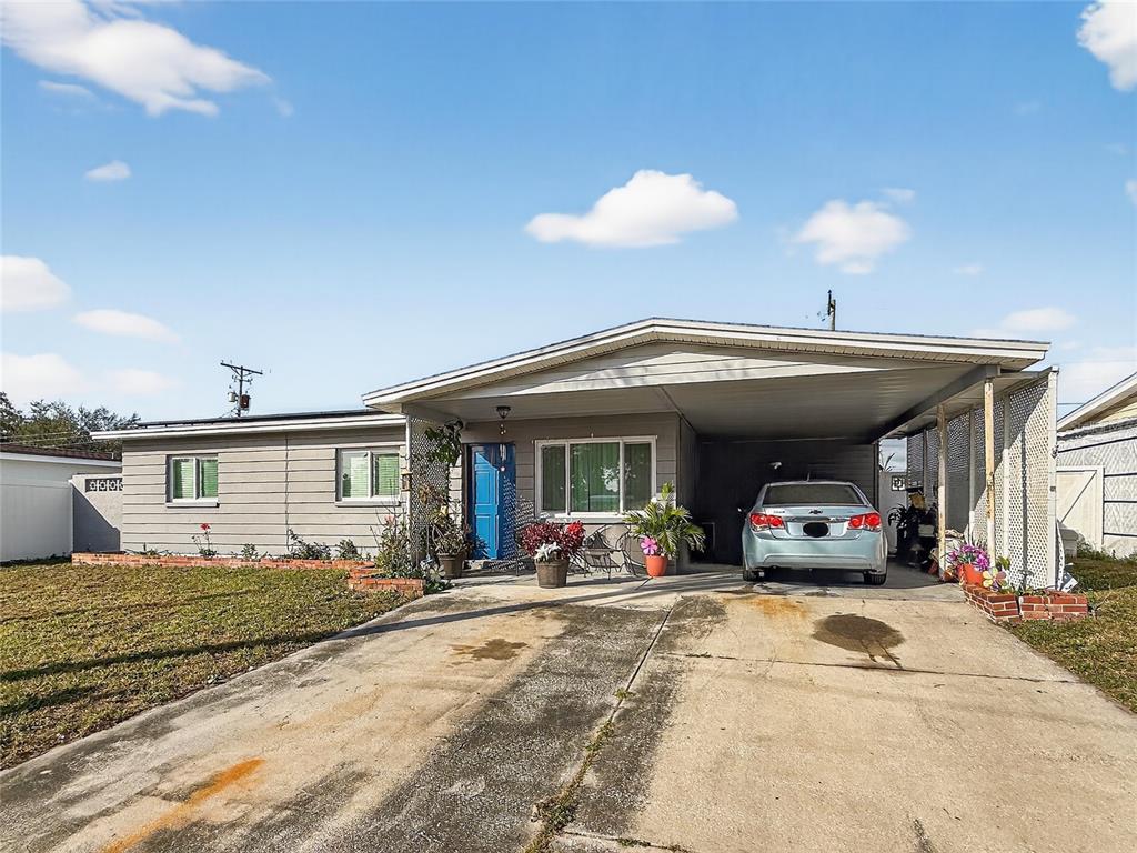 A single-story house with gray siding, a blue front door, and an attached carport — 8009 CORNWALL LANE, TAMPA, FL