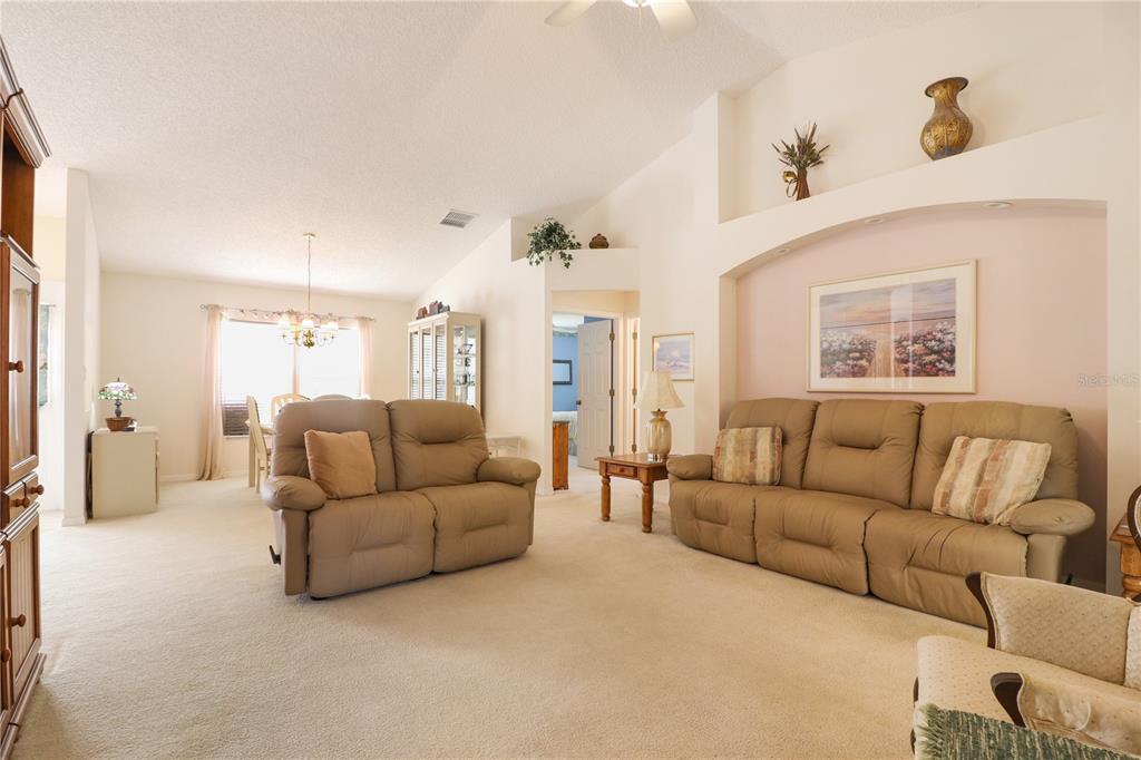 A living room with beige carpet, two tan sofas, and a decorative wall niche — 25339 CRESTWATER DRIVE, LEESBURG, FL