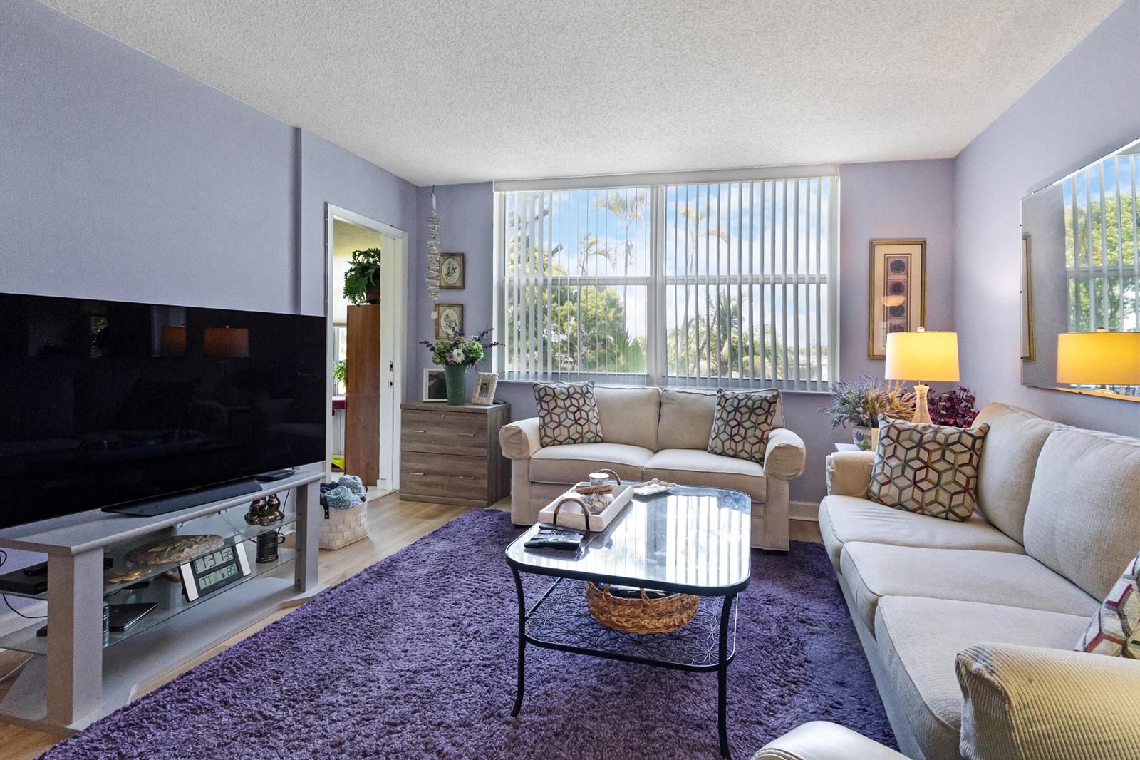 A living room features a purple rug, two beige sofas, a glass coffee table, and television — 6870 Royal Palm Boulevard # 202m, Margate FL 33063, MARGATE, FL
