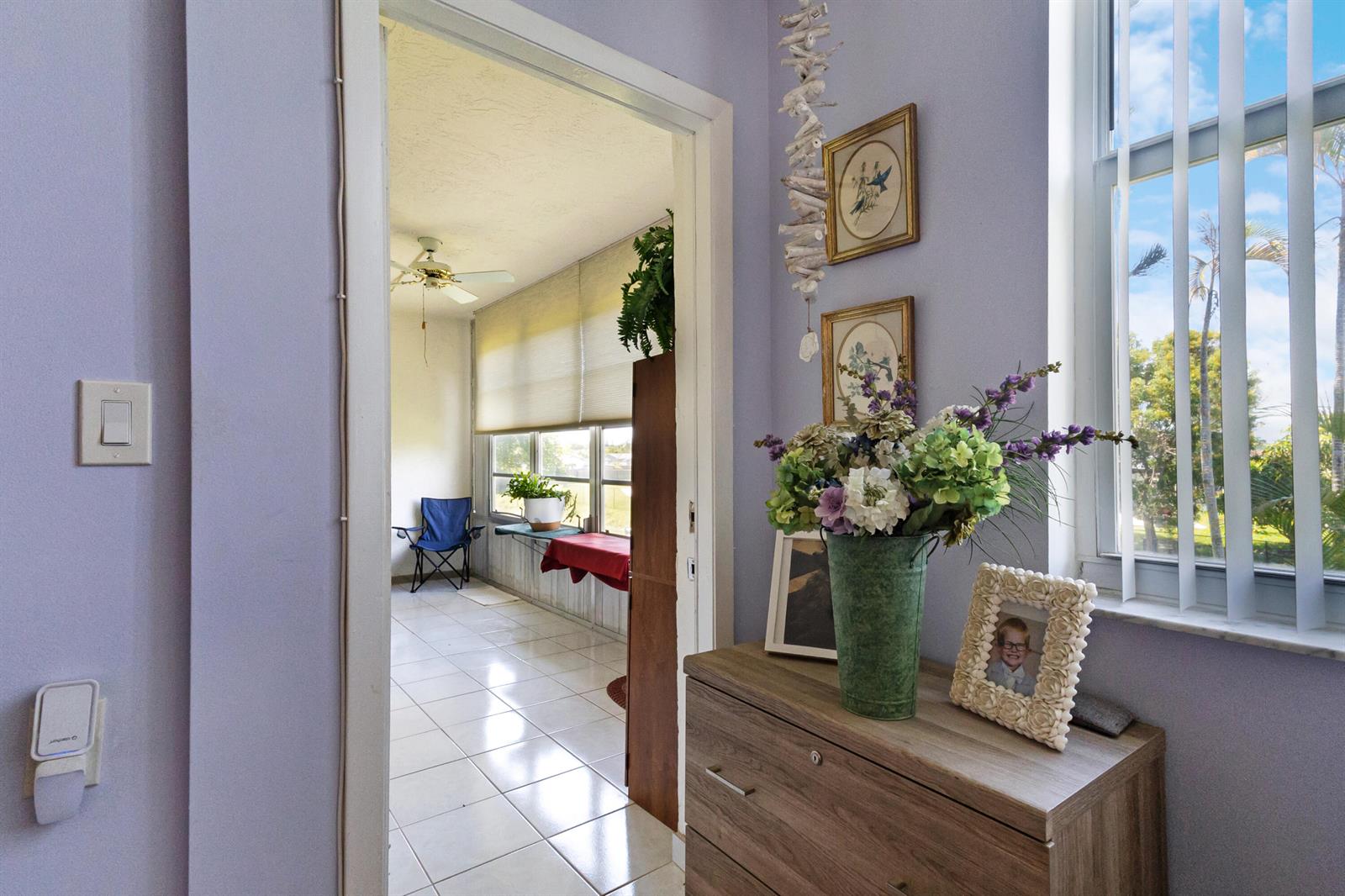 A light purple hallway leads into a sunroom with tiled floors and large windows — 6870 Royal Palm Boulevard # 202m, Margate FL 33063, MARGATE, FL