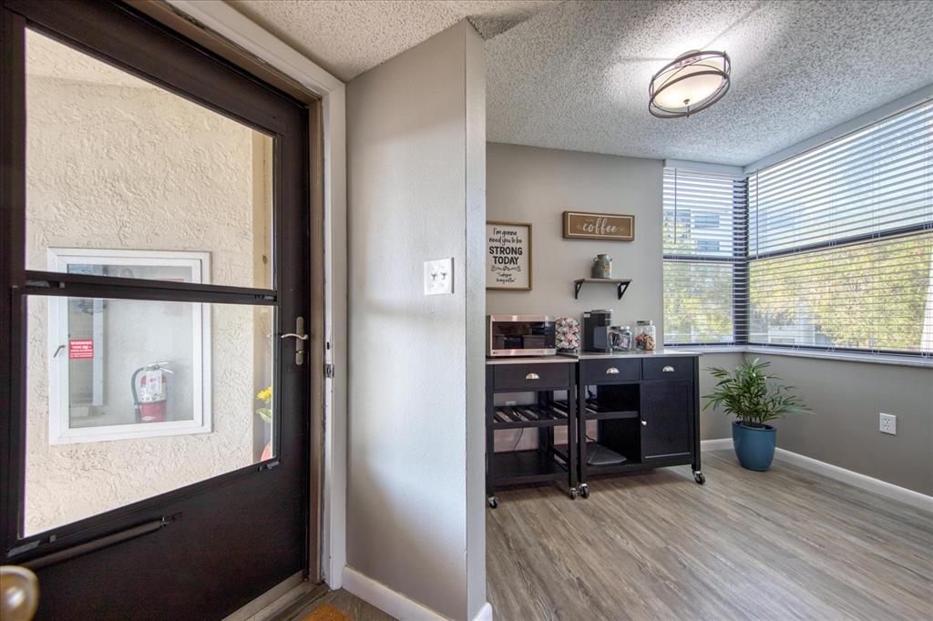 A room with wood-look flooring, a coffee station, and a large window with blinds — 1324 PASADENA AVENUE S UNIT 201, SOUTH PASADENA, FL