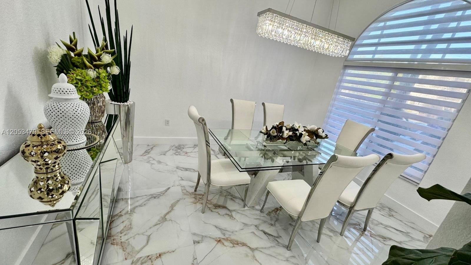 A dining room features a glass table, white chairs, a crystal chandelier, and marble flooring — 11500 SW 153rd Ave # 1, Miami FL 33196, MIAMI, FL