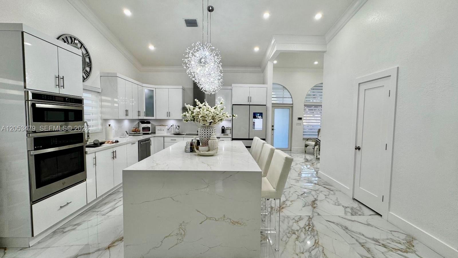 A modern white kitchen features a large marble island, stainless steel appliances, and tile flooring — 11500 SW 153rd Ave # 1, Miami FL 33196, MIAMI, FL