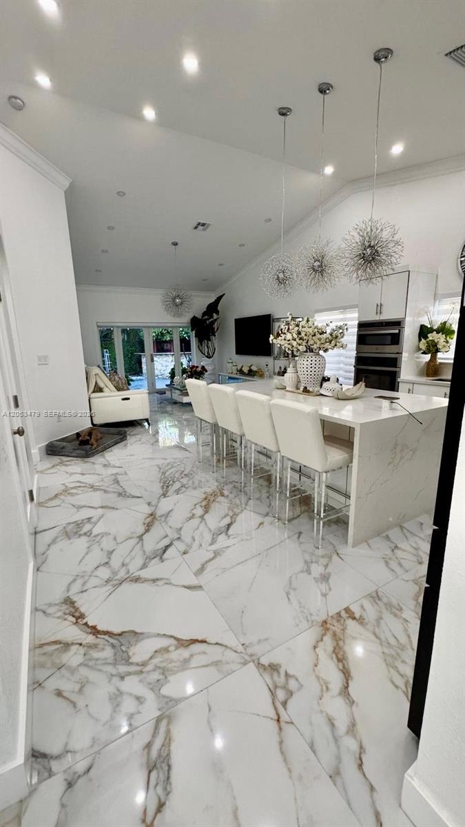 A modern kitchen features a large marble island with white bar stools and pendant lighting — 11500 SW 153rd Ave # 1, Miami FL 33196, MIAMI, FL