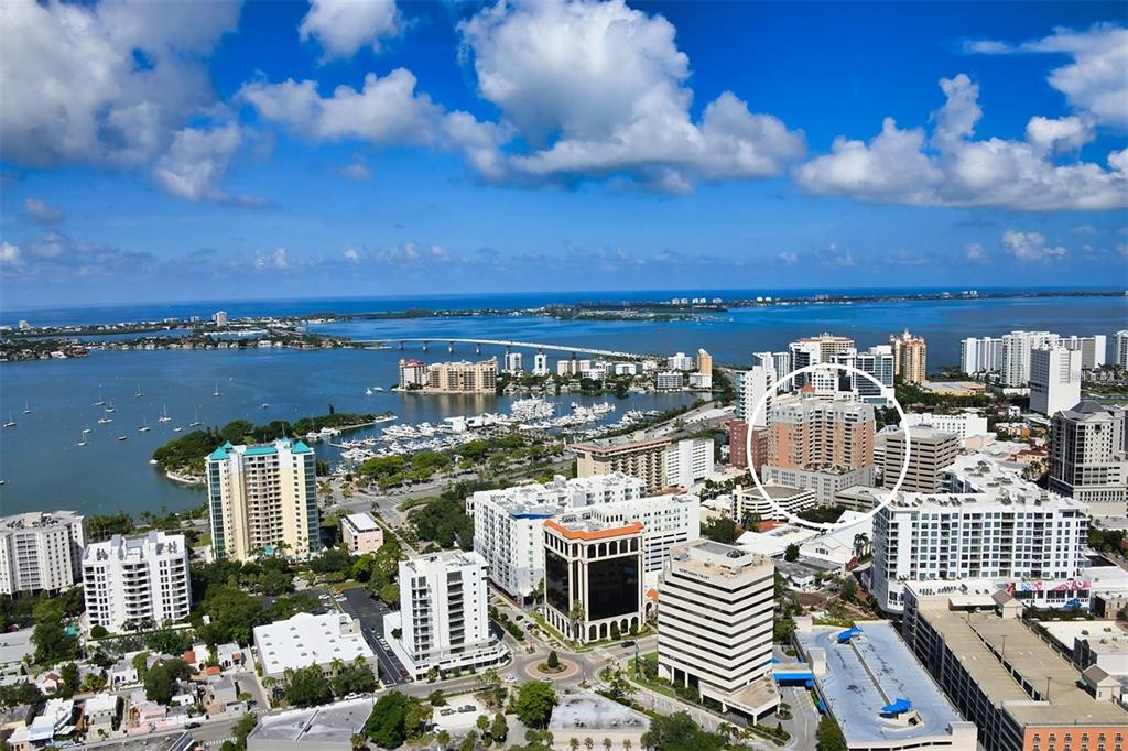 An aerial view shows a coastal city skyline with a high-rise building circled in white — 1350 MAIN STREET UNIT 709, SARASOTA, FL