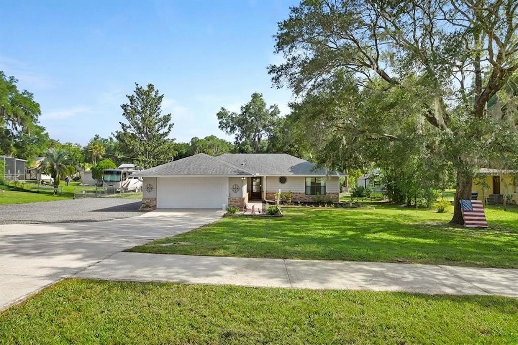 A single-story house with a two-car garage and a large front lawn with trees — 235 W RETTA STREET, DE LEON SPRINGS, FL