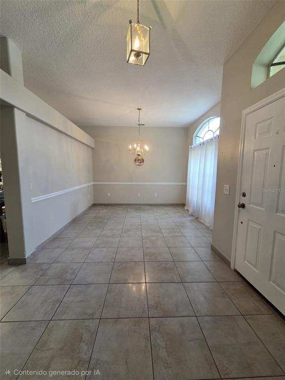 An empty dining room features tile flooring, two hanging light fixtures, and a white door — 407 MARTIGUES DRIVE, KISSIMMEE, FL