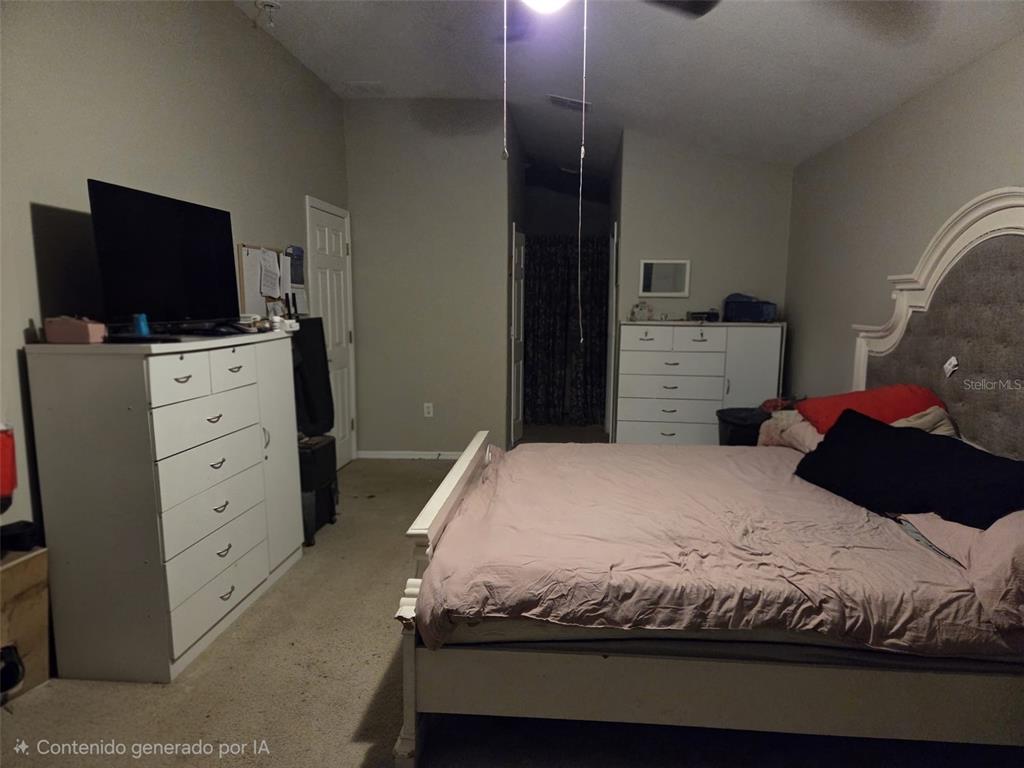 A bedroom features a large bed, two white dressers, and a television — 407 MARTIGUES DRIVE, KISSIMMEE, FL