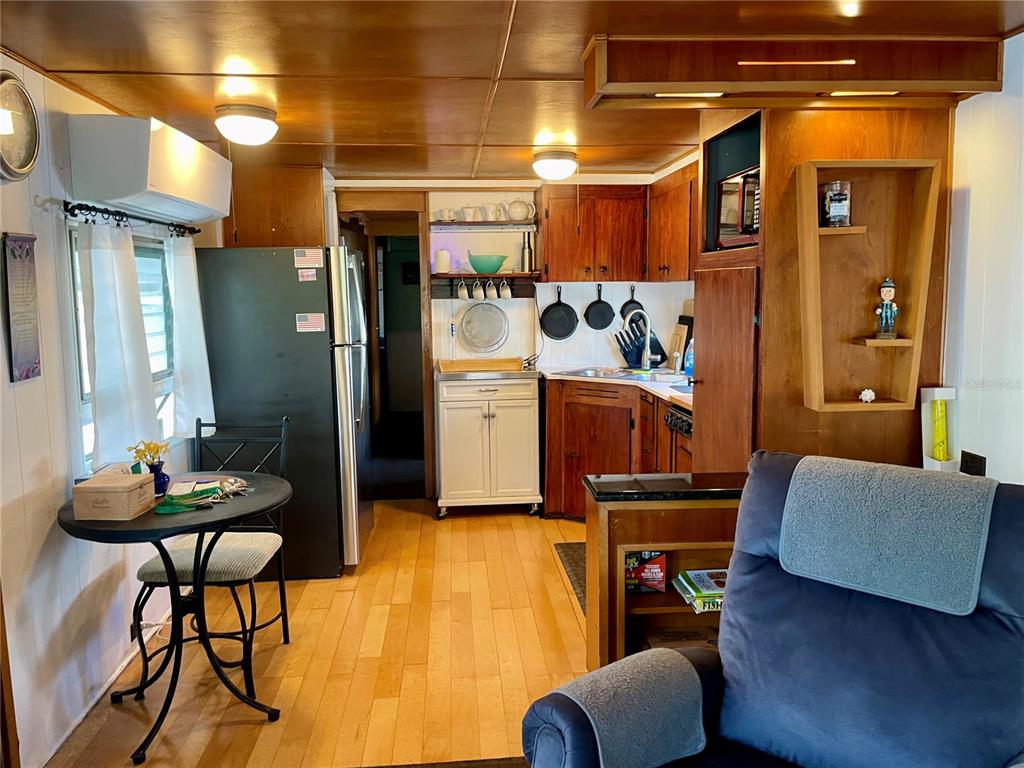 A kitchen with wood-paneled walls and ceiling, light wood flooring, and a small dining area — 13 TENNESSEE STREET, PALMETTO, FL