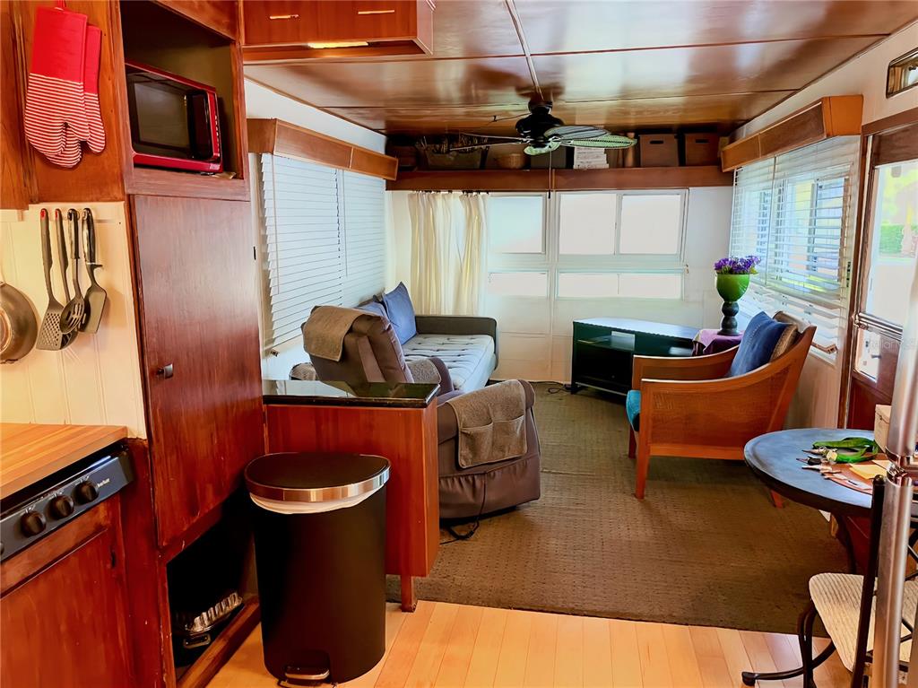 A living room with wood paneling, a ceiling fan, a sofa, and a small dining area — 13 TENNESSEE STREET, PALMETTO, FL