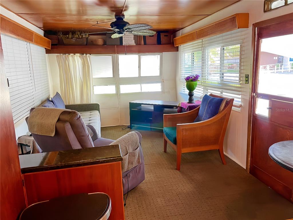 A sunroom features a ceiling fan, brown carpeting, wood-paneled walls, and a view of outdoors — 13 TENNESSEE STREET, PALMETTO, FL