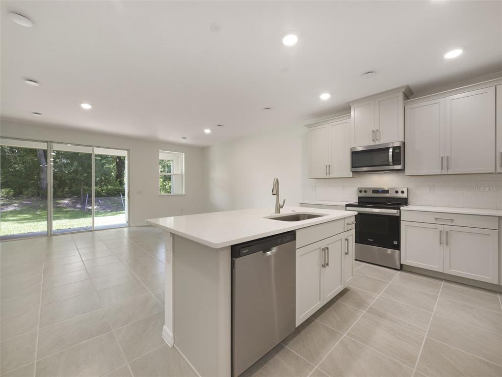 A modern kitchen with light gray cabinets, white countertops, and stainless steel appliances — 1649 GREENLEAF WOOD COVE, OVIEDO, FL