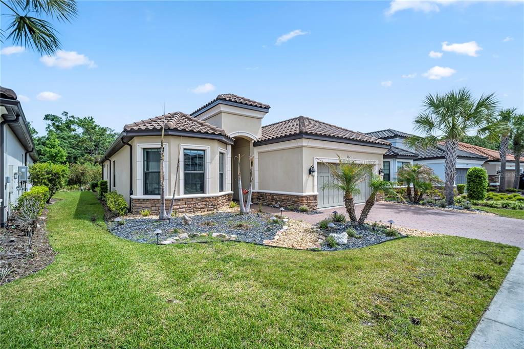 A single-story house with a tan stucco exterior, stone accents, and a tiled roof — 20161 UMBRIA HILL DRIVE, TAMPA, FL
