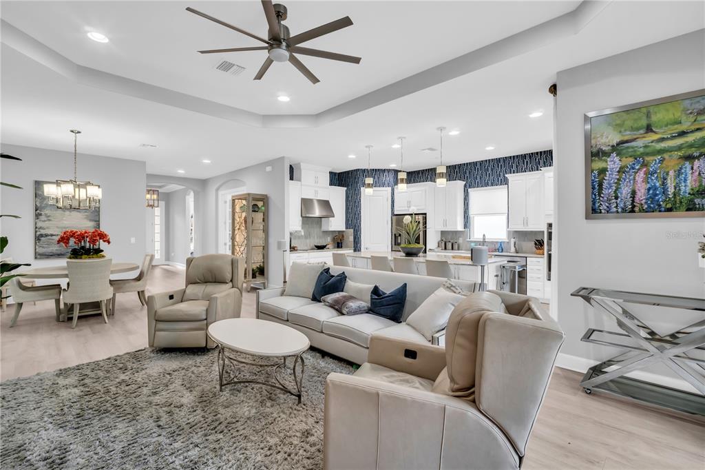 An open-concept living room and kitchen feature a gray sofa, light flooring, and pendant lighting — 20161 UMBRIA HILL DRIVE, TAMPA, FL