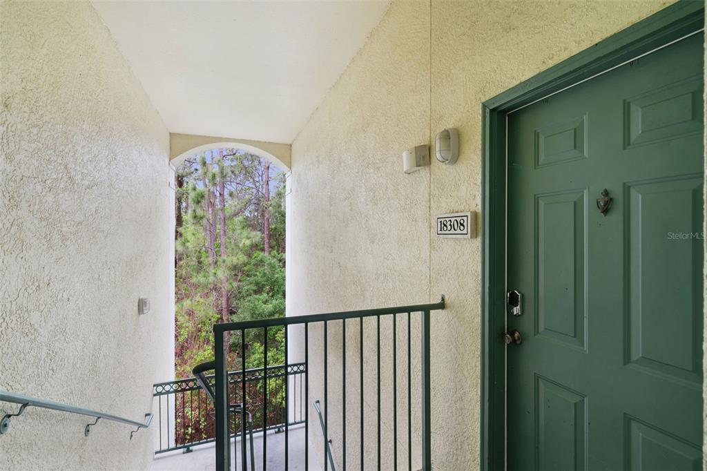An outdoor stairwell leads to a green front door with the number 18308 — 8921 LEGACY COURT UNIT 18-308, KISSIMMEE, FL