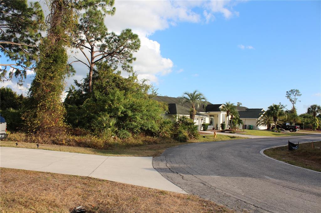 A view of a house exterior with a driveway, landscaping, and trees under a blue sky — 2250 STONEGATE CIRCLE, PORT CHARLOTTE, FL
