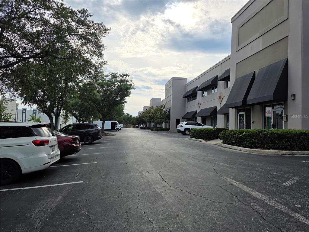 An exterior view of a commercial office building with a parking lot and trees — 7802 KINGSPOINTE PARKWAY UNIT 202, ORLANDO, FL