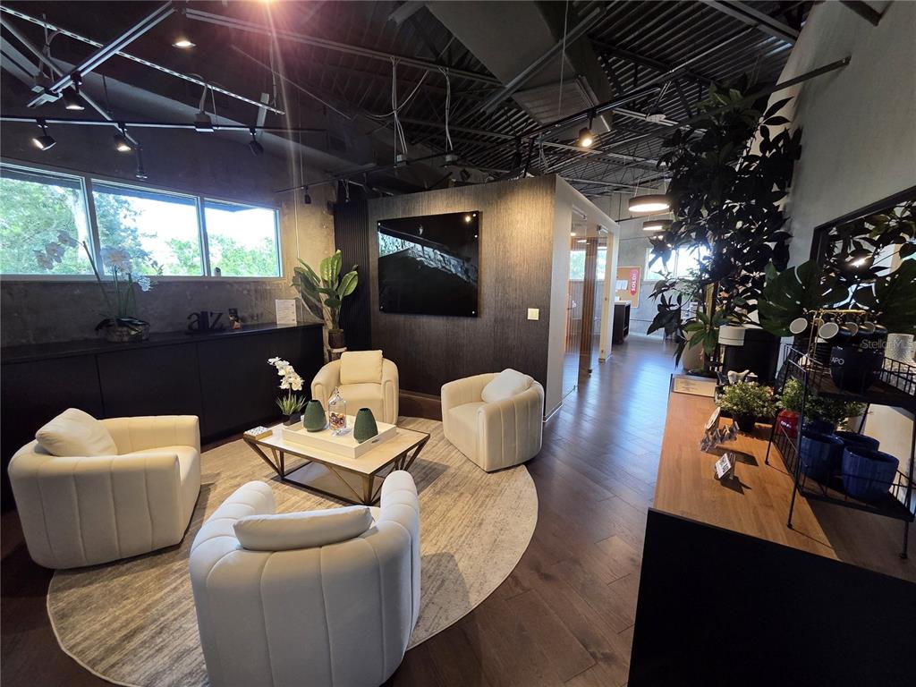 A modern office lounge features four white armchairs arranged around a coffee table on a rug — 7802 KINGSPOINTE PARKWAY UNIT 202, ORLANDO, FL