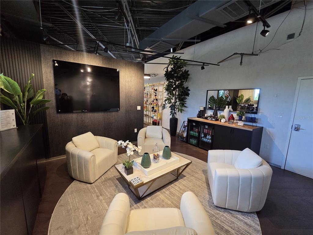 A modern lounge area features four white armchairs arranged around a central coffee table — 7802 KINGSPOINTE PARKWAY UNIT 202, ORLANDO, FL