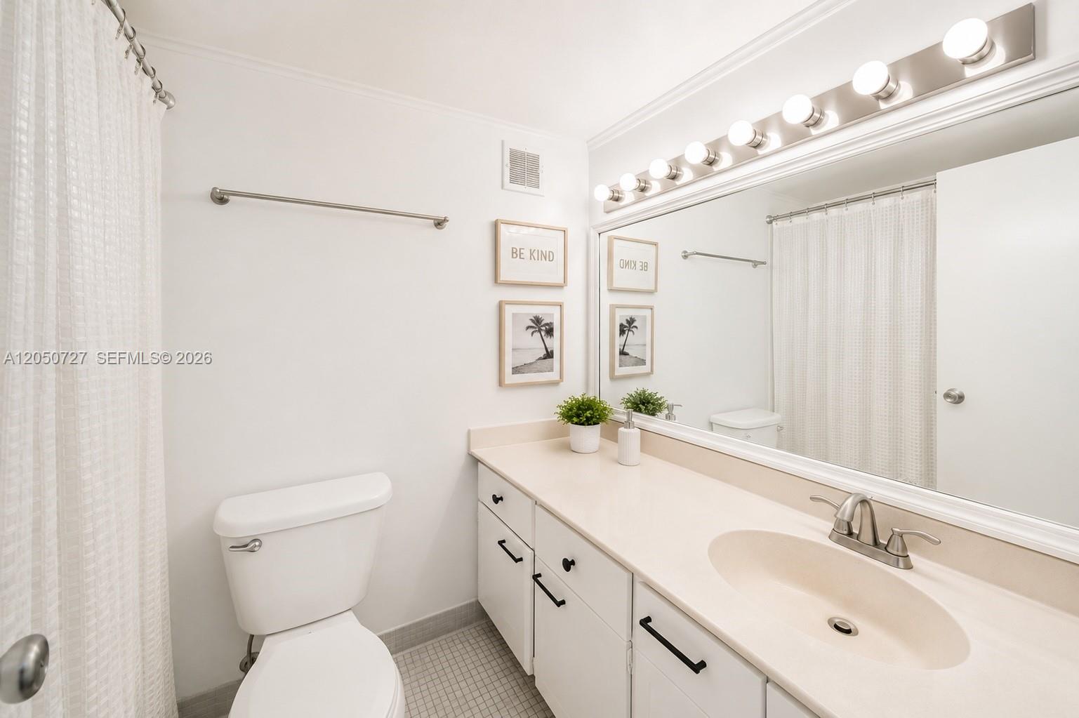 A bathroom features a white vanity with a beige countertop, a toilet, and a mirror — 1200 West Ave, Miami Beach FL 33139, MIAMI BEACH, FL