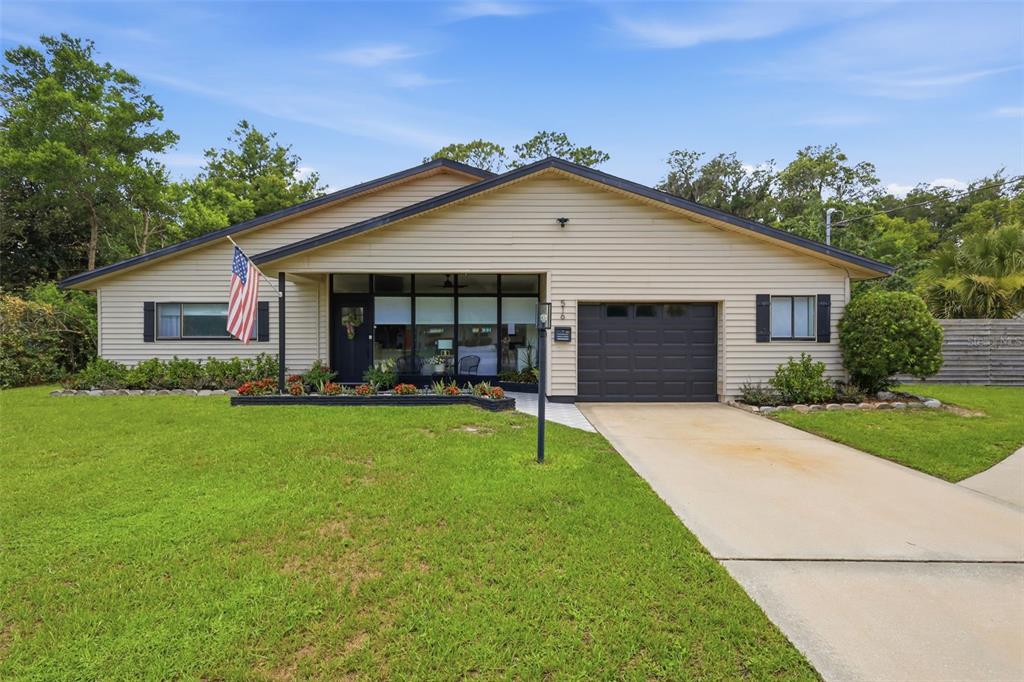 A single-story house with beige siding, a dark garage door, and a front lawn — 516 N MCDONALD AVENUE, DELAND, FL