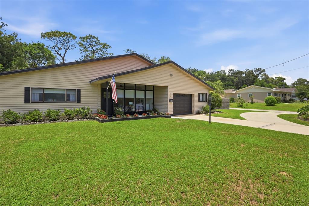 A single-story house with beige siding, a front-facing garage, and a large grassy lawn — 516 N MCDONALD AVENUE, DELAND, FL