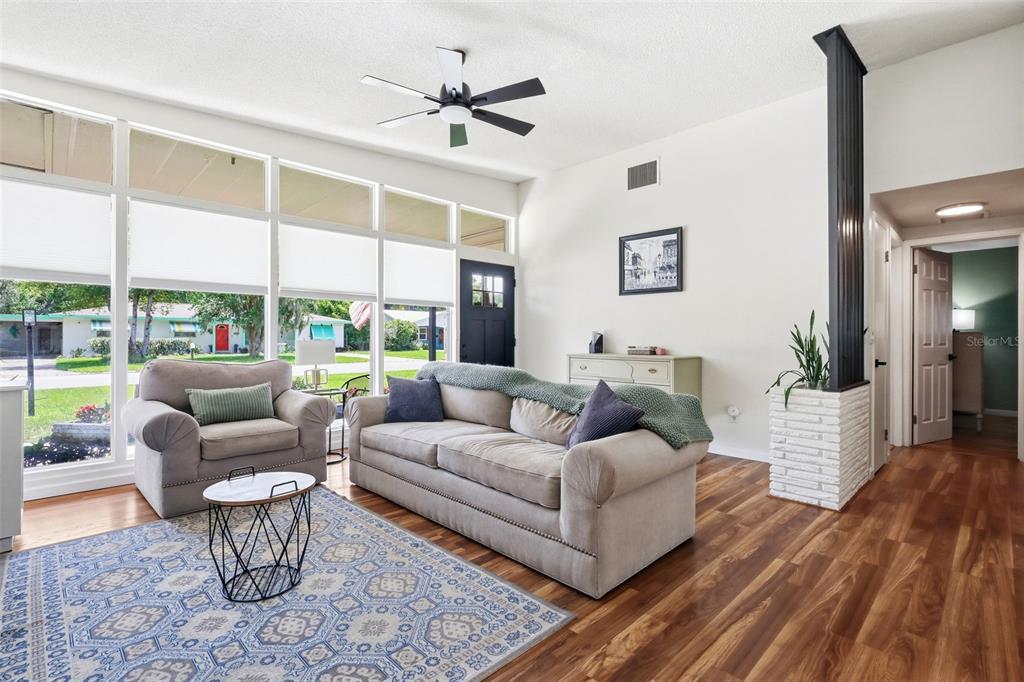A living room features wood-look flooring, a large window wall, and a ceiling fan — 516 N MCDONALD AVENUE, DELAND, FL