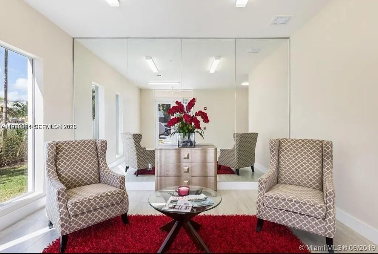 A room features two patterned armchairs, a glass coffee table, and a large mirrored wall — 555 E Dania Beach Blvd # 5, Dania Beach FL 33004, DANIA BEACH, FL
