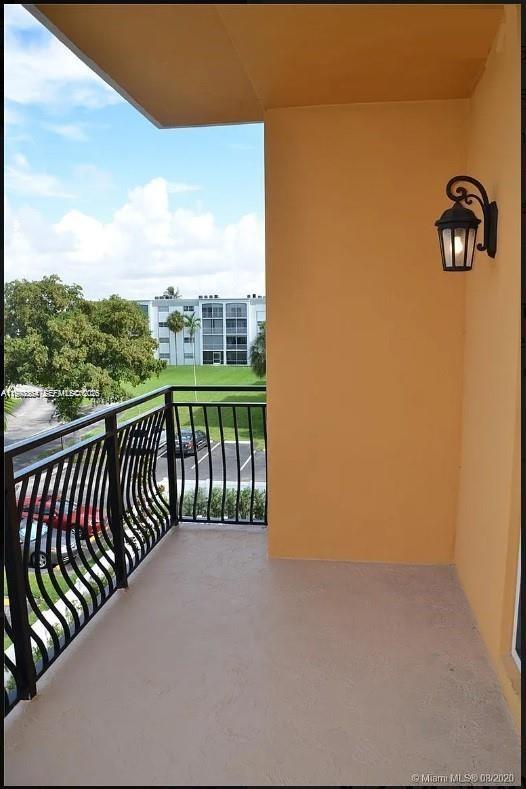 A balcony with a black metal railing overlooks a parking lot and a nearby building — 555 E Dania Beach Blvd # 5, Dania Beach FL 33004, DANIA BEACH, FL