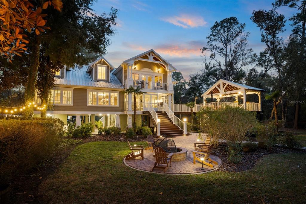 A two-story house with a raised deck, outdoor staircase, and a circular stone fire pit — 174 NE 972ND STREET, BRANFORD, FL