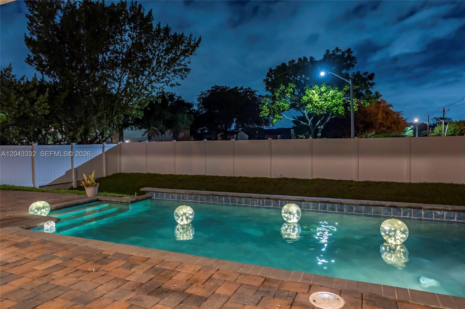 A backyard swimming pool at night features glowing orb lights floating on the water — 7601 Cavalia Dr, Davie FL 33328, DAVIE, FL