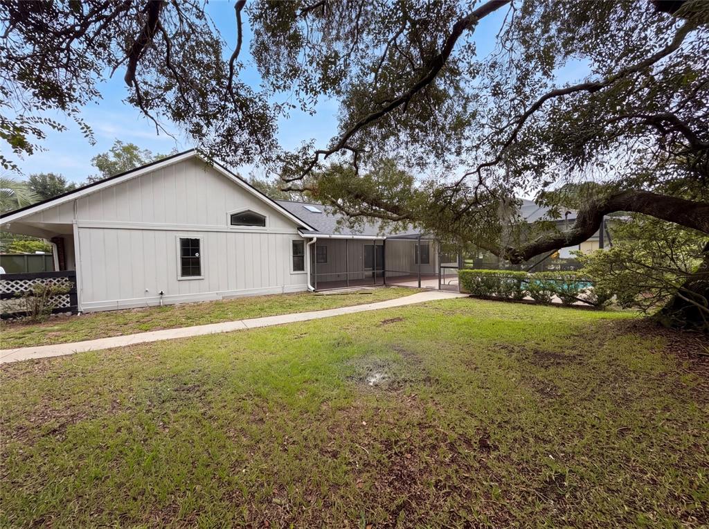 A side view of a house with light siding, a screened-in patio, and a pool — 5082 SW 31ST STREET, OCALA, FL