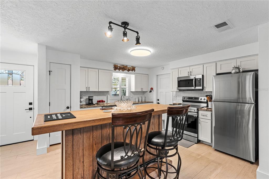 A kitchen features white cabinets, stainless steel appliances, granite countertops, and a subway tile backsplash — 2005 ORIOLE LANE, SOUTH DAYTONA, FL
