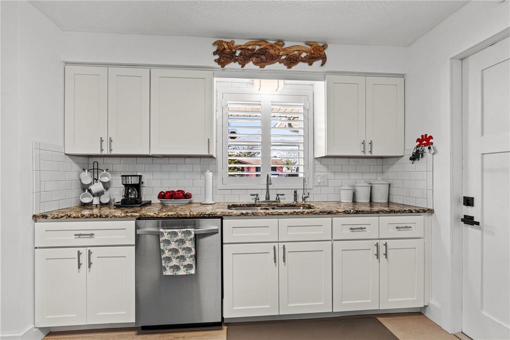 A living room with a gray sofa, marble coffee table, and television opens to a kitchen — 2005 ORIOLE LANE, SOUTH DAYTONA, FL