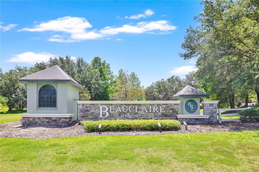 A stone and stucco entrance sign for Beauclaire Ranch Club stands on a grassy lawn — GRAND OAK LANE, TAVARES, FL