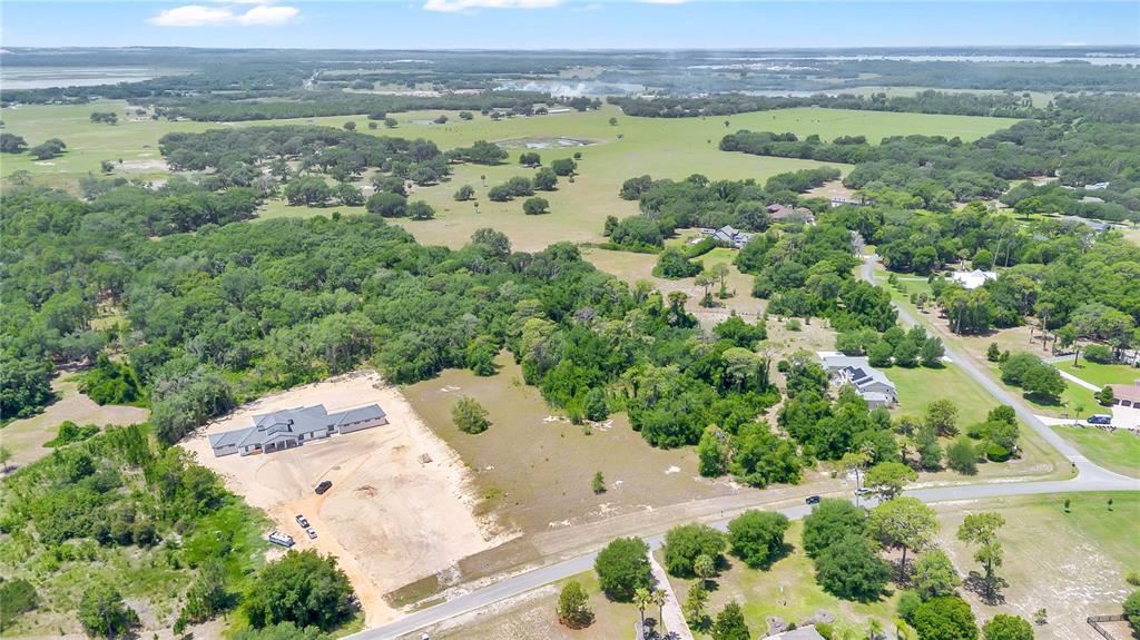 An aerial view shows a large house under construction on a rural, wooded lot — GRAND OAK LANE, TAVARES, FL