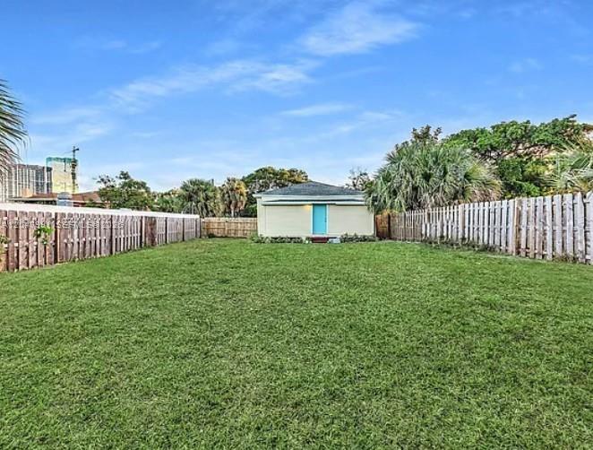 A large, grassy backyard features a detached building with a blue door and wooden fencing — 719 9th St, West Palm Beach FL 33401, WEST PALM BEACH, FL