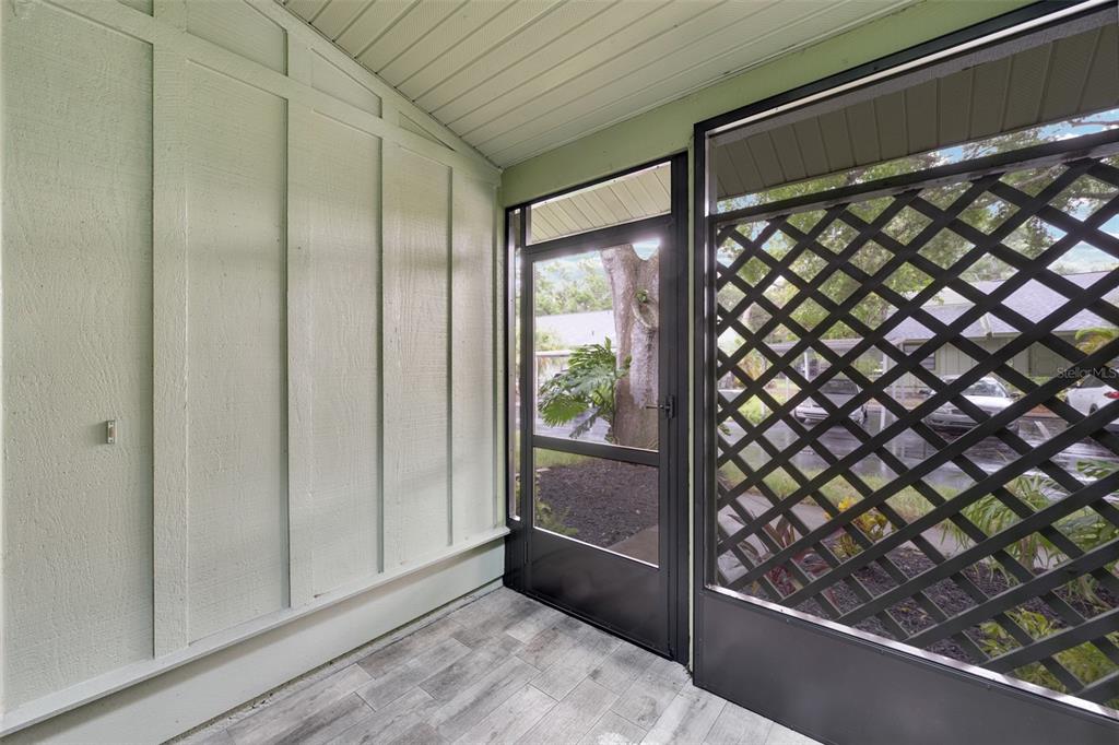 A screened-in porch features light-colored vertical wood paneling, gray wood-look tile flooring, and lattice screening — 5015 BARRINGTON CIRCLE UNIT 201, SARASOTA, FL