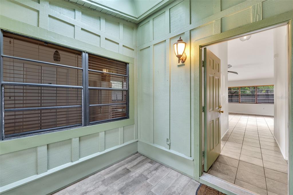 A light green exterior entryway with a window, wall sconce, and door leading inside — 5015 BARRINGTON CIRCLE UNIT 201, SARASOTA, FL