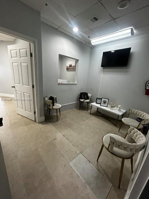 A waiting room features light-colored tile flooring, several chairs, a small table, and a television — 900 W 49th St Suite 420, Hialeah FL 33012, HIALEAH, FL